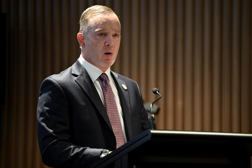 Seorang eksekutif olahraga Paralimpiade Australia berdiri di podium selama pidato.