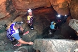 A group walk into a cave, wearing headlights.