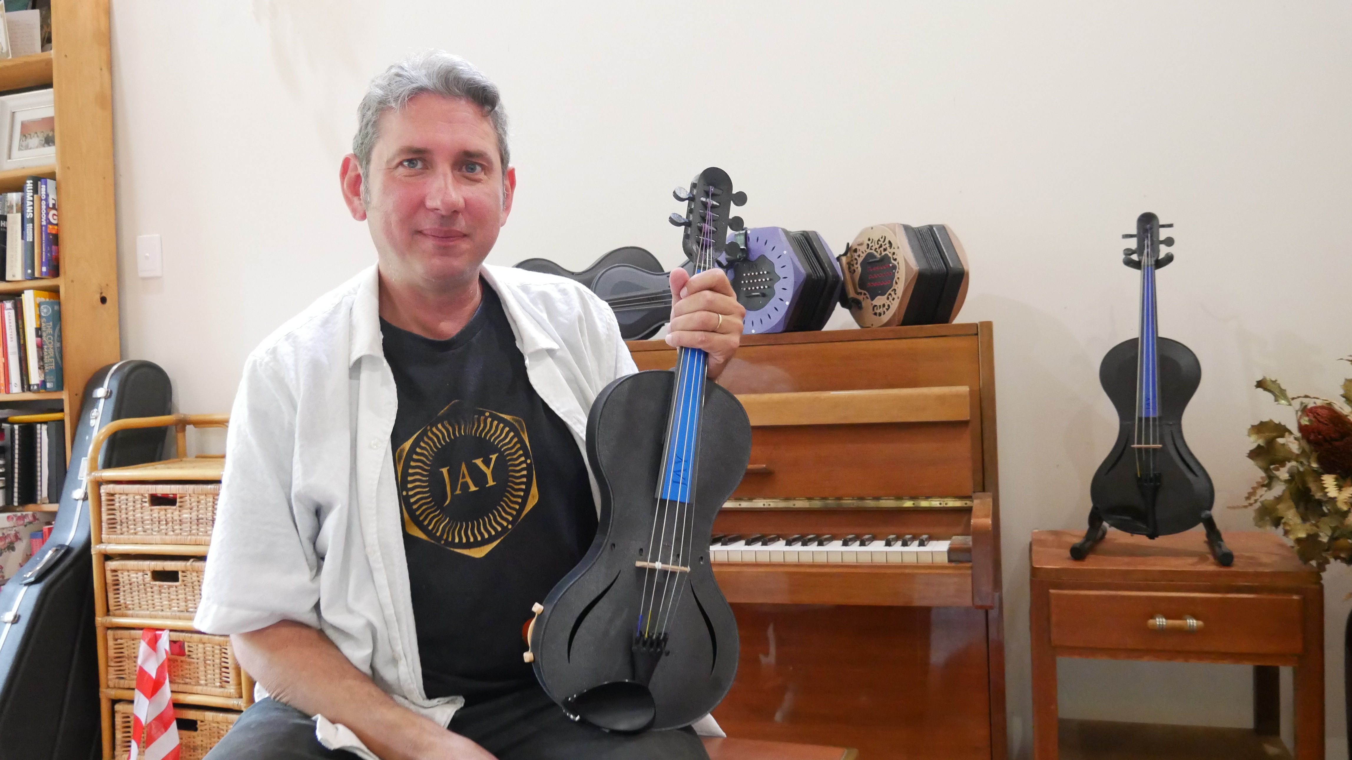 A medium shot of a man holding a violin 