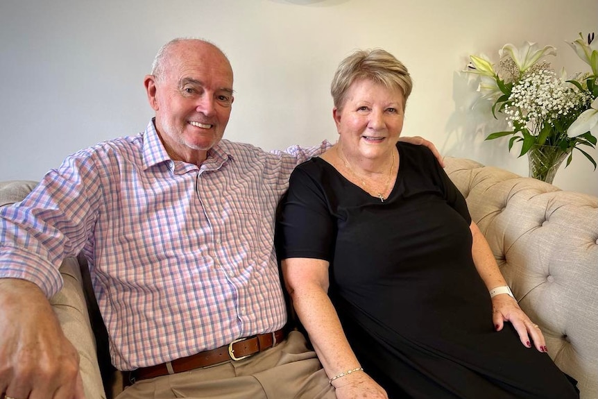 Man in long sleeve check shirt and woman in black dress on a couch