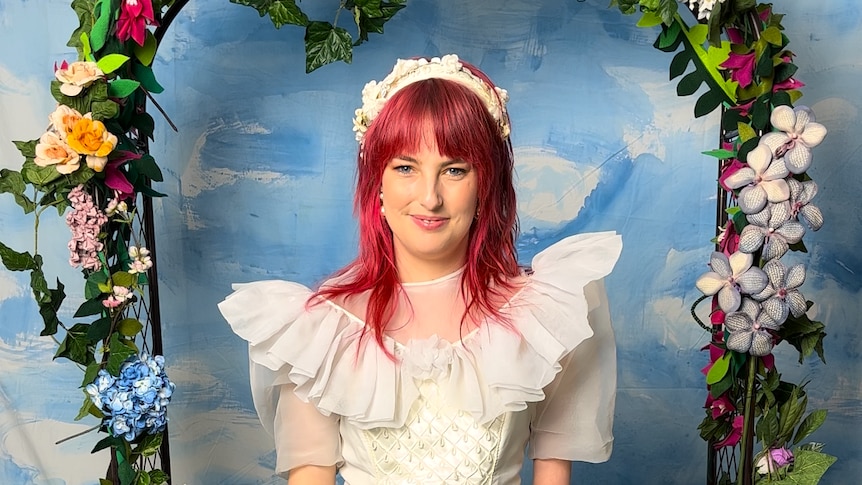 Madeleine is in her late 20’s pink , has pink hair a limb difference and wears a wedding dress 