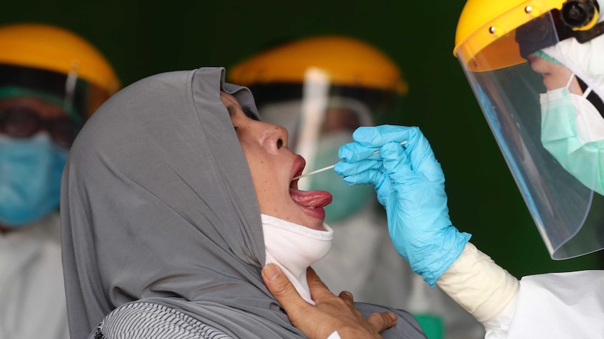 Woman wearing face covering has nasal swab taken