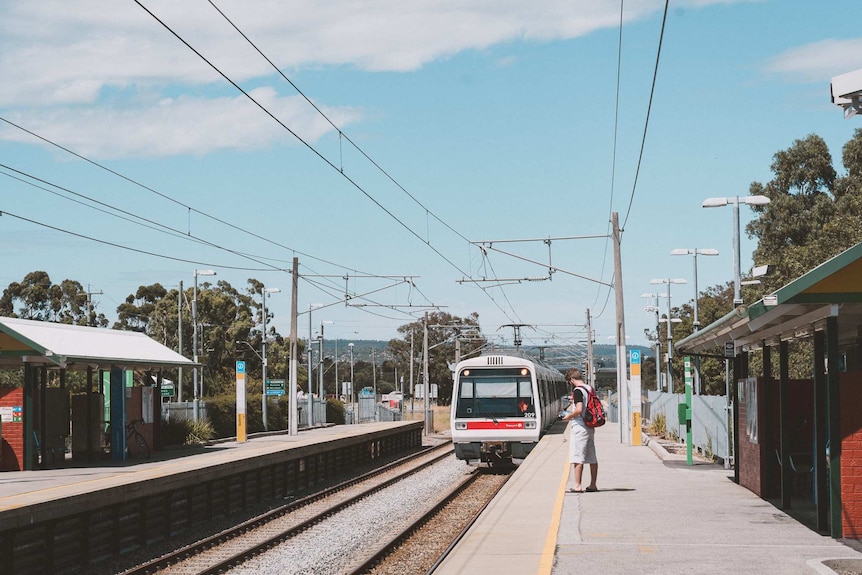 A train pulls into Seaforth Station in Gosnells with a passenger standing on the platform waiting.