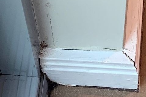 Mould in corner and cracked paint and skirting board.