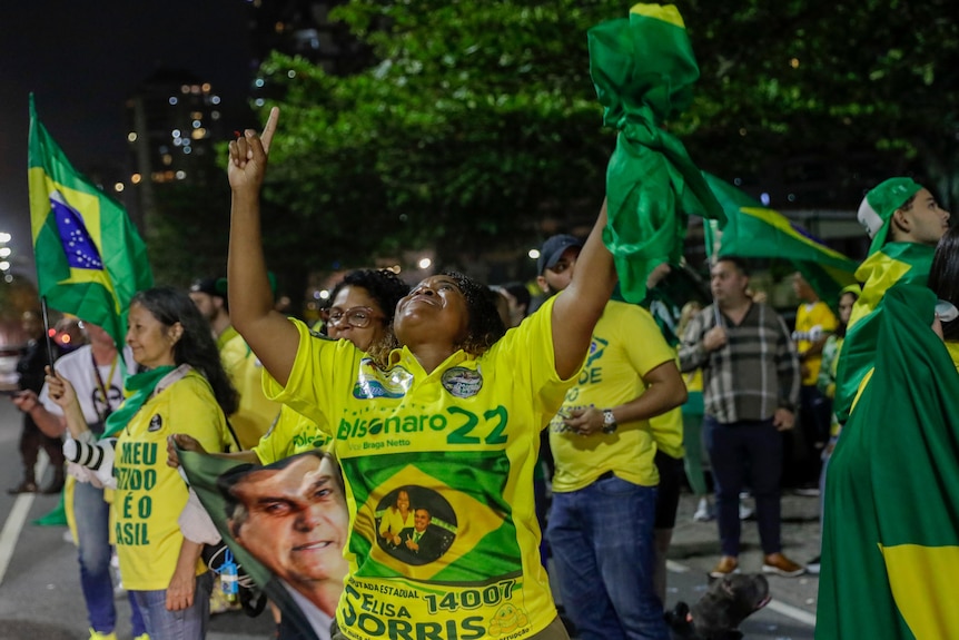 黄绿相间的女人举起双臂庆祝，晚上站在街上