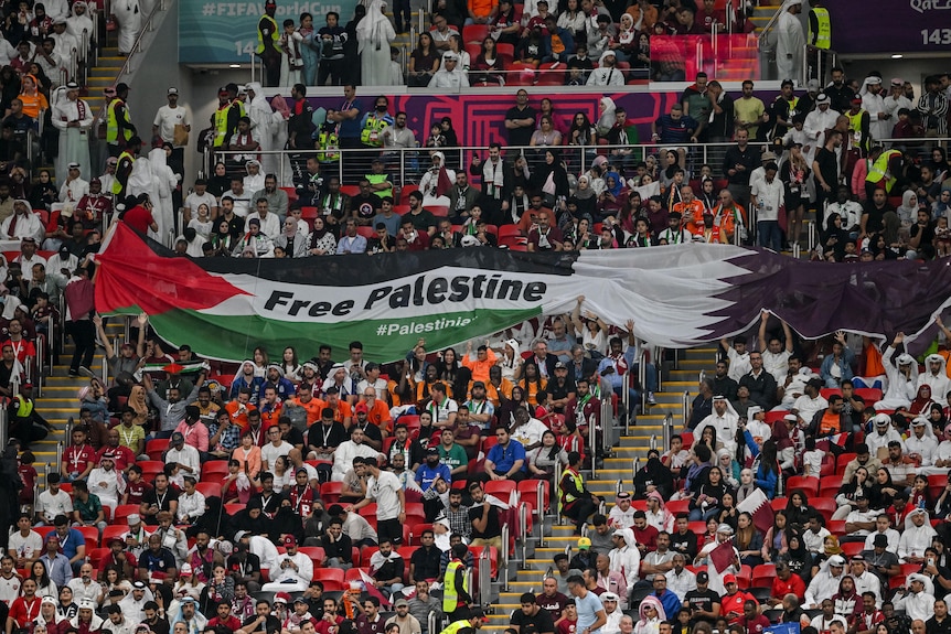 Soccer fans hold a large banner with a Palestinian flag during a game