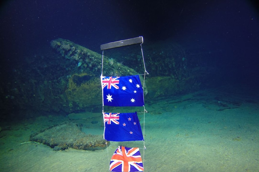 underwater photo of Australian, NZ and British flags commemorating the lost crew of HMAS AE1