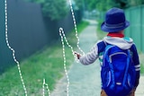 A child walks down a path holding the hand of an invisible parent to depict when kids can walk to school and play outside alone.