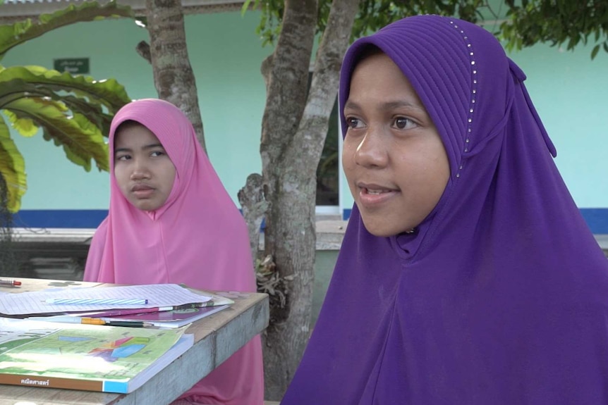 Two Muslim schoolgirls wearing pink and purple hijabs.