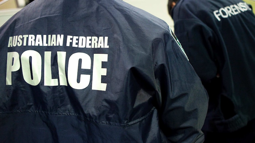 Deux personnes non identifiées portant des vestes avec "Police fédérale australienne" et "Médecine légale" sur le dos.