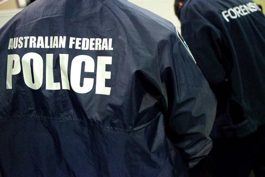 Two unidentified people wearing jackets with "Australian Federal Police" and "Forensics" on the back.