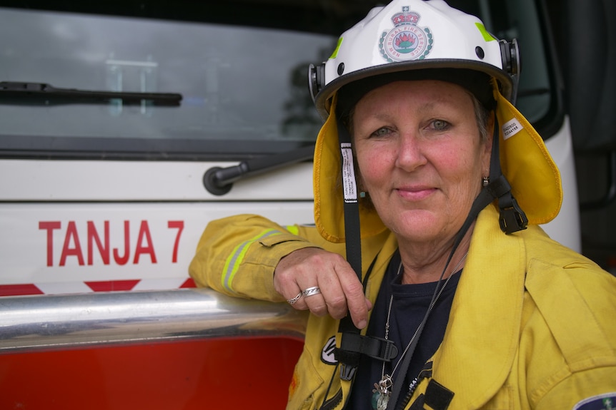 Portrait of woman in firefighting uniform stand with truck, smiling