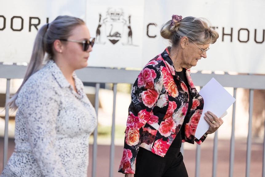 Two women leaving a courthouse holding paperwork.  