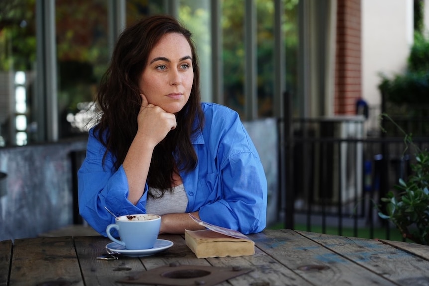 A woman wearing a blue shirt sits at a table