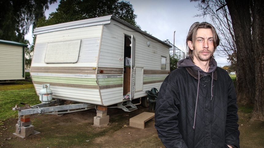 Luke Skinner standing in front of his current home, a caravan.