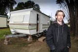 Luke Skinner standing in front of his current home, a caravan.