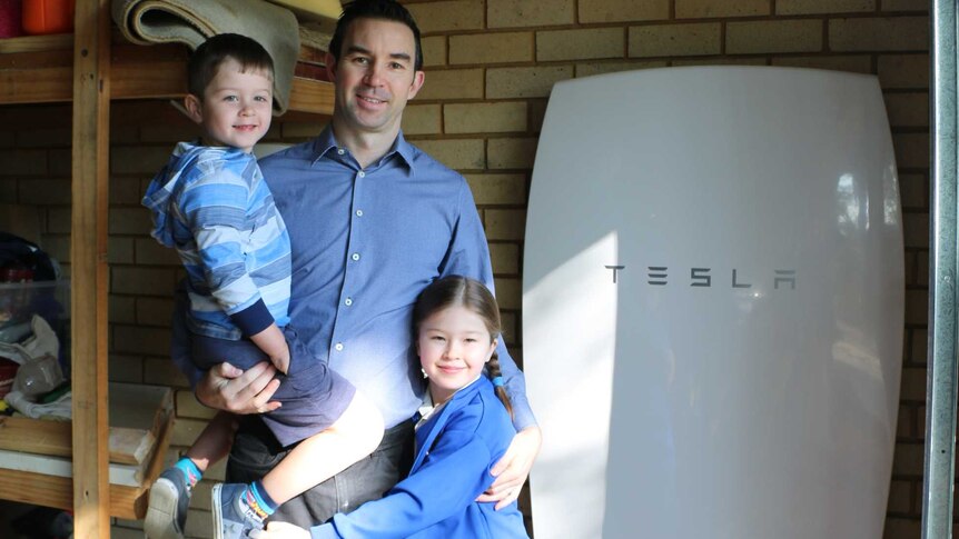 Murray Green and his children Aaron and Madeline pose next to their Tesla solar battery