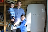 Murray Green and his children Aaron and Madeline pose next to their Tesla solar battery
