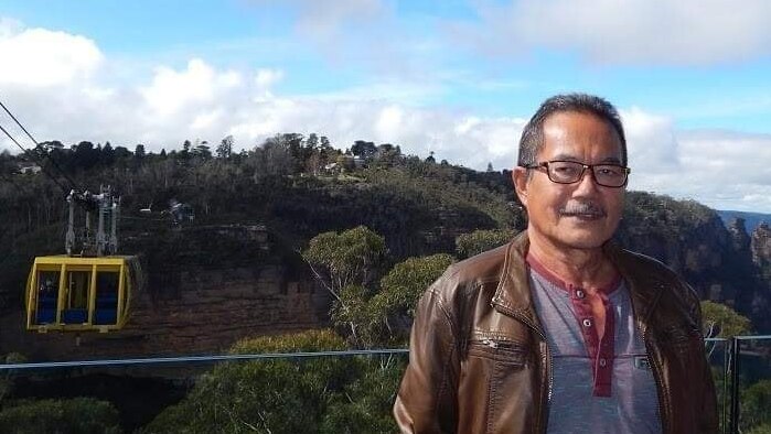 A man smiling in a tourist photo in the Blue Mountains