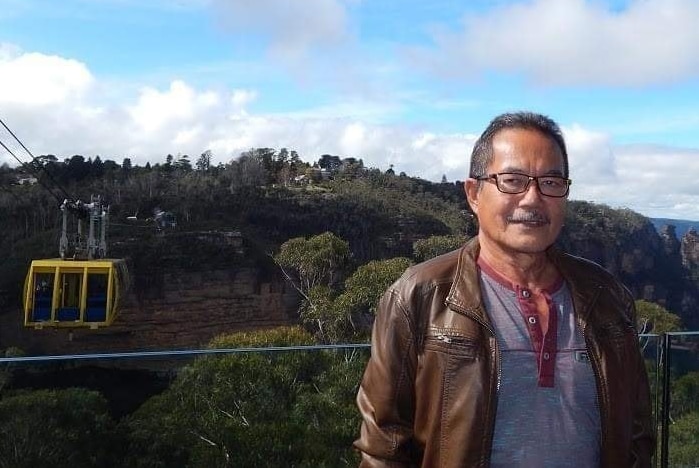 A man smiling in a tourist photo in the Blue Mountains