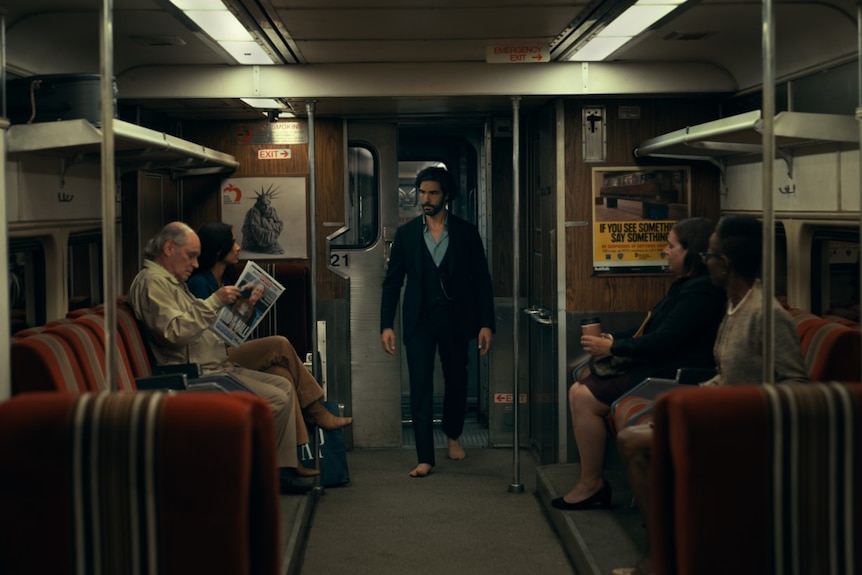 A bearded man in bare feet marches through a subway carriage in Madame Web.