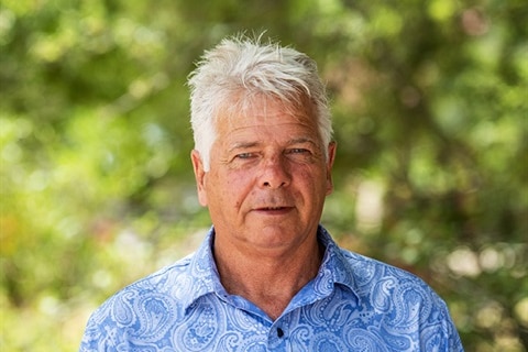 A middle aged man with white hair and a blue shirt. 
