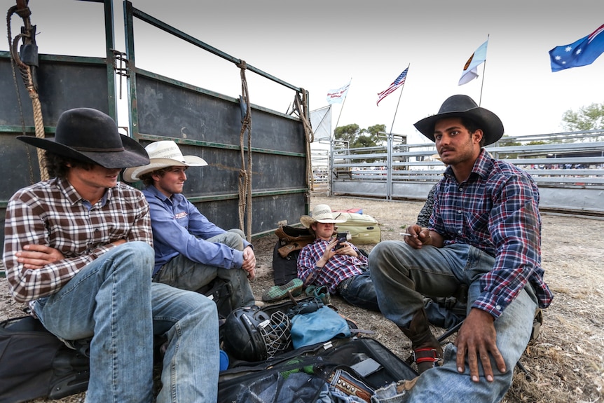 Haider Al Hasnawi with Sam Woodall and other cowboys sitting around at the rodeo.