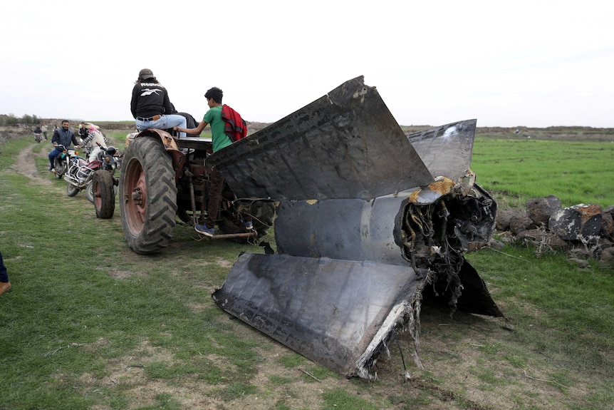 A tractor pulls a part of a missile in Quneitra