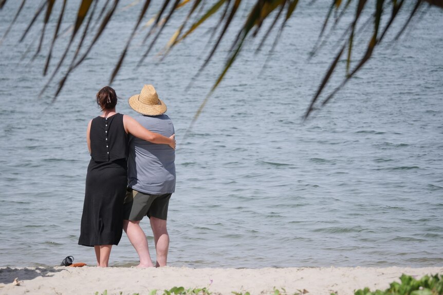 A woman embraces a person as they face out toward the water on the Gold Coast Broadwater