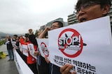 South Korean protestors hold signs saying Stop Max Thunder!