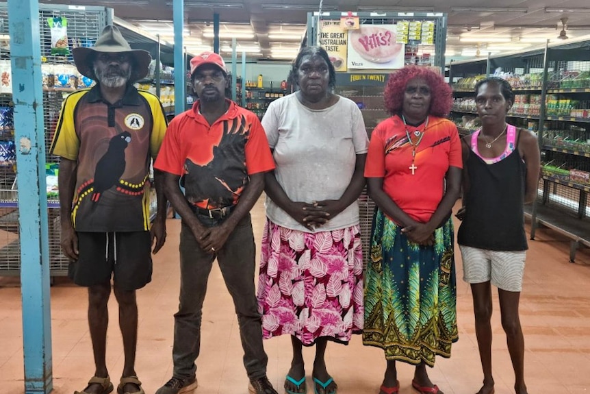 Five traditional owners of Wadeye stand together in a line in the community's store. 