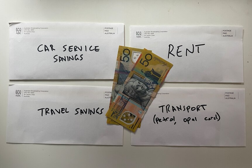 Four 'cash stuffed' envelopes and some $50 bills, with labels like 'car service savings' and 'rent'.