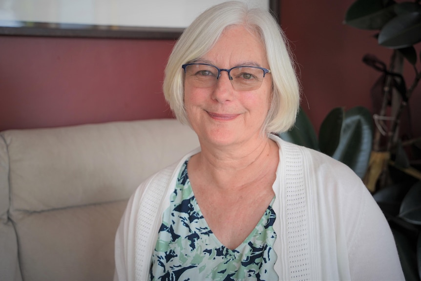 A woman with white hair sits on a couch.