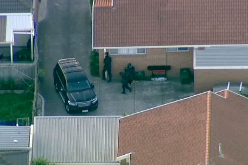 Aerial view of heavily armed police offices hiding behind a house at Epping.