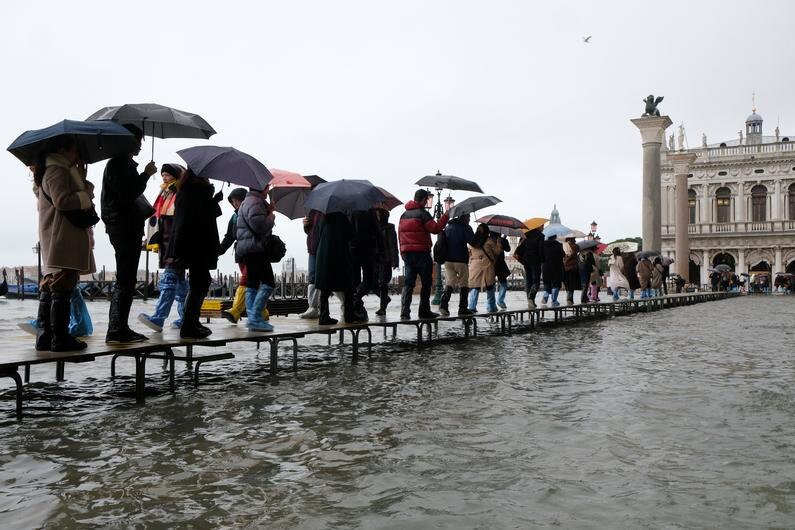 People walk on catwalk in floods of Venice.