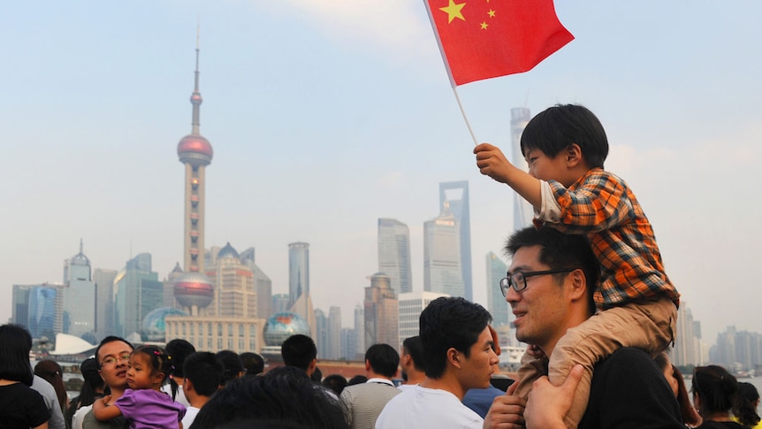 A boy on his father's shoulders waves the flag of China on the country's national day