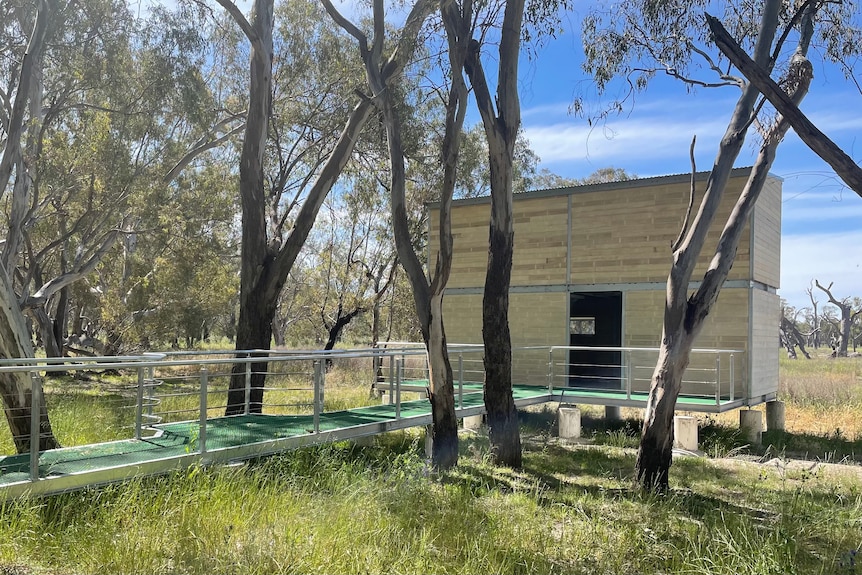 A small, two storey wooden building in bushland, with a ramp leading up to it. 