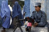 An Afghan policeman keeps watch as women arrive at a polling station