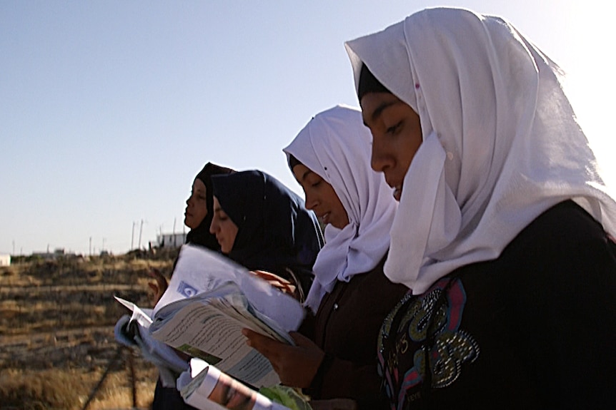 Palestinian teenager Reem and her friends, from the village of Tuba, walk past an Israeli settlement on their way to school.