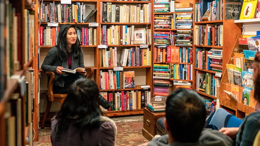 Woman sits at the front of a crowded room in a bookstore