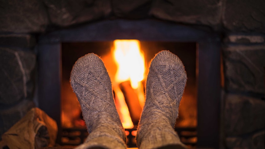 Feet in socks in front of a glowing wood fire