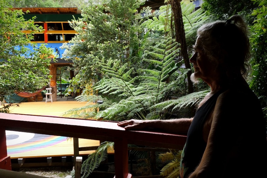 A man sitting down silhouetted with a colourful building and Yin/Yang ground mural behind.