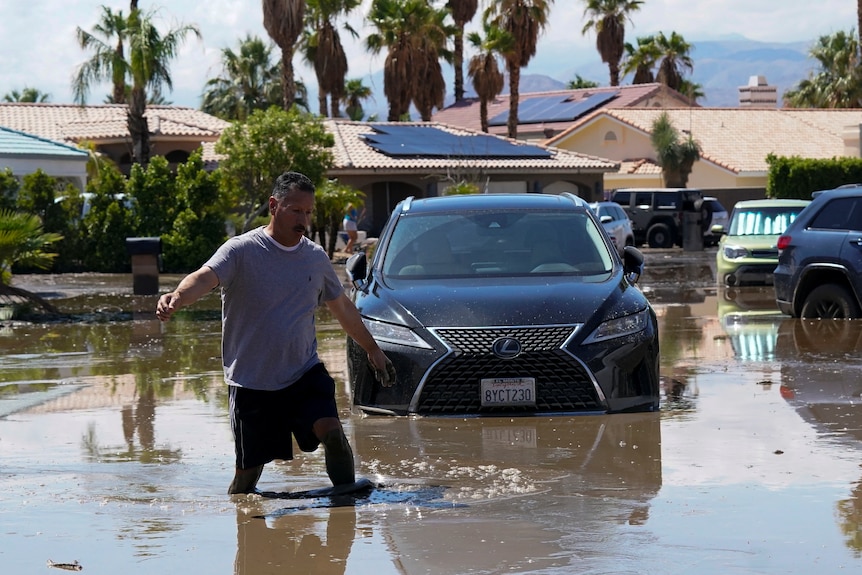 man wades through water in suburban street
