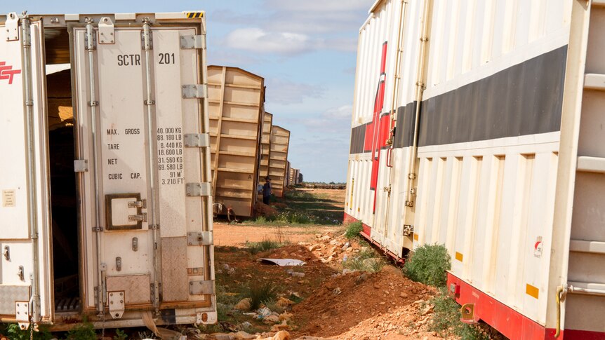 A rough line of freight containers left in the desert.