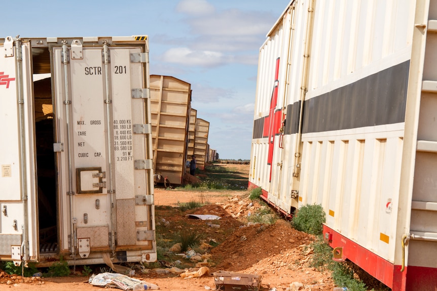 A rough line of freight containers left in the desert.