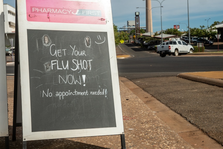 A sign on the footpath pushing for more people to get their flu vaccination in regional Queensland.