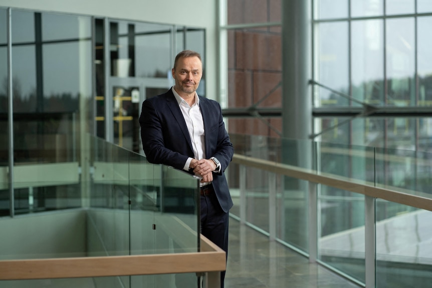 A man poses for a professional portrait in an office environment