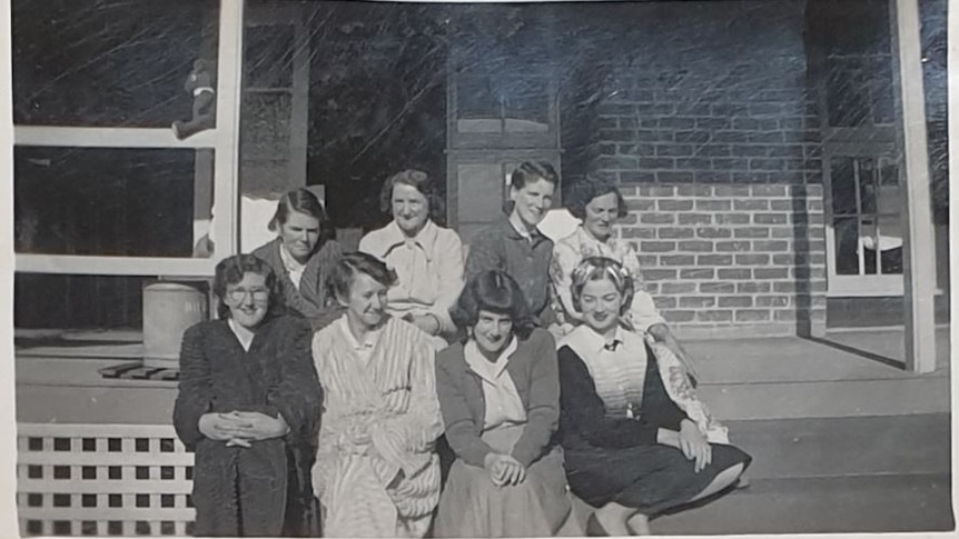 An old black and white photograph of women sitting on a porch.