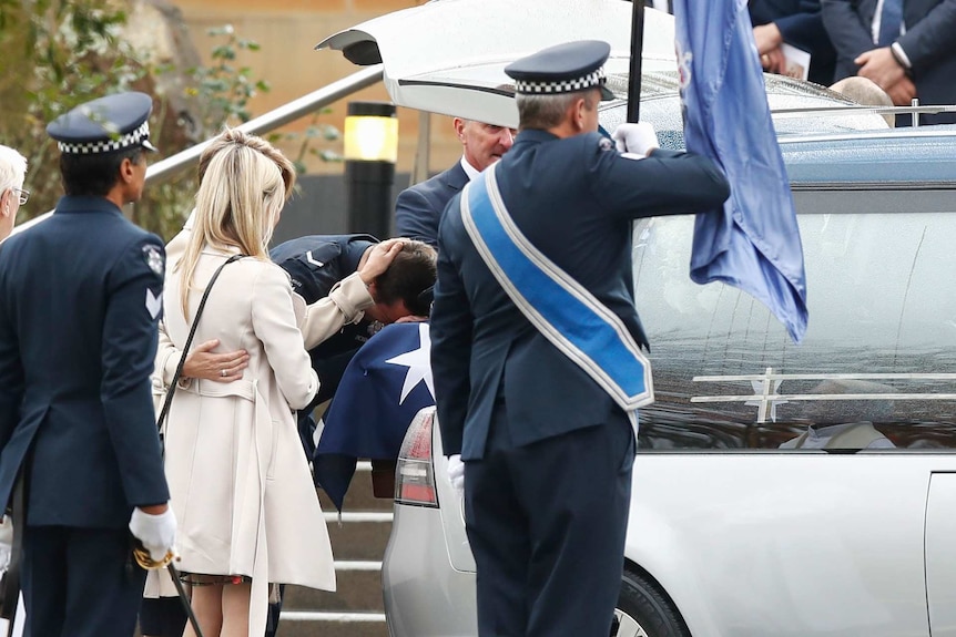 Constable Alex Prestney lays his head on his brother's coffin and his mother, Belinda, lays a h and on his head.