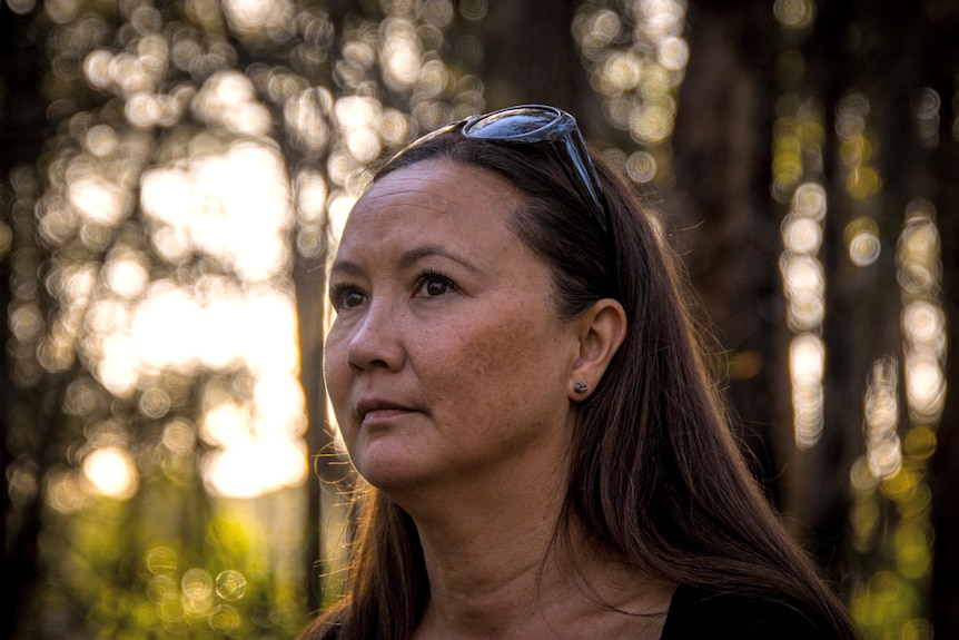 woman stands in a forrest looking out to distance 